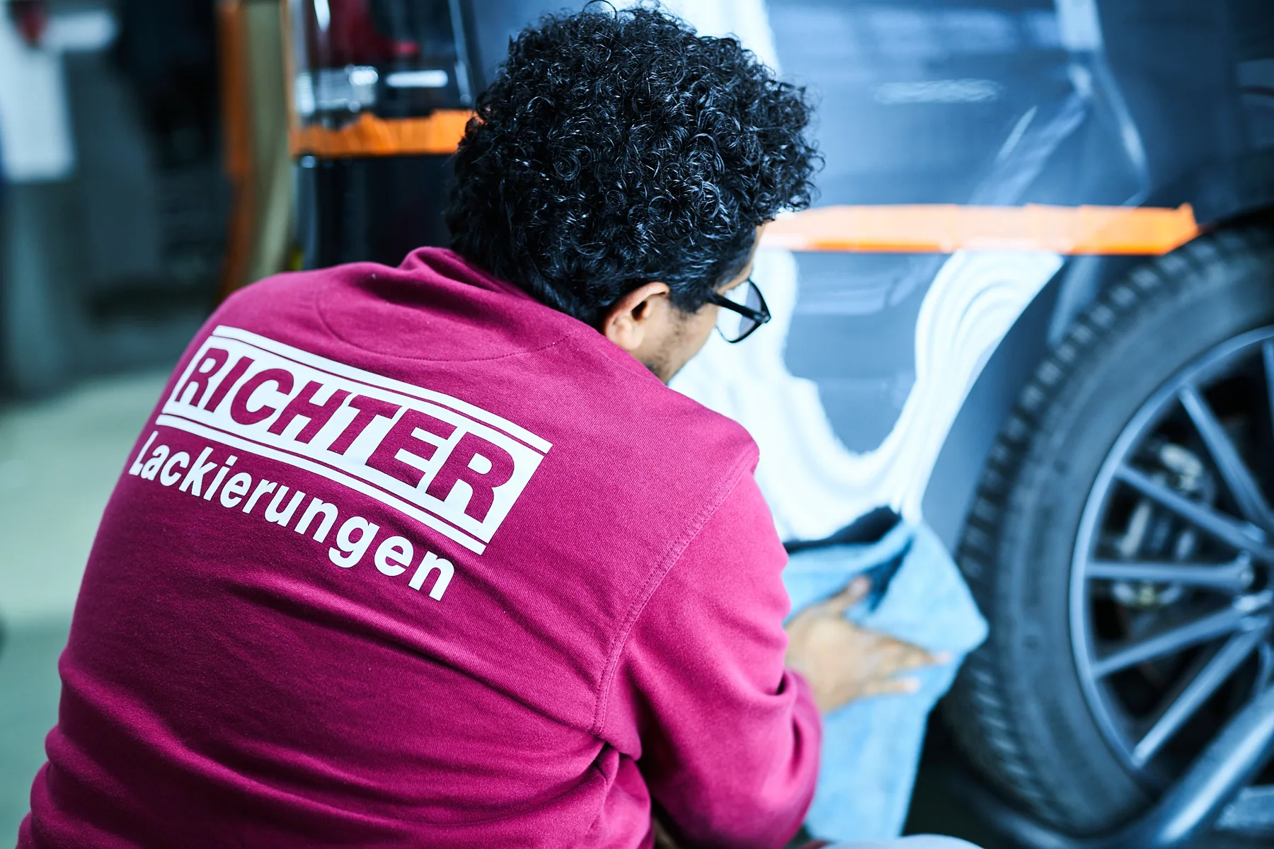 Lackierer von Richter bei der präzisen Arbeit an einem Fahrzeugteil