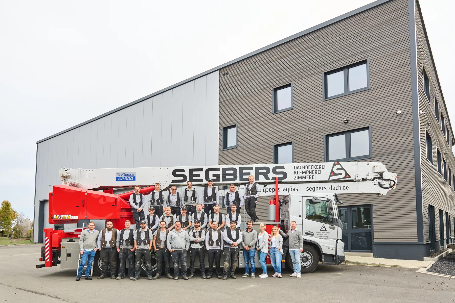 Team von Segbers Bedachungen vor dem eigenen Kran und Firmengebäude